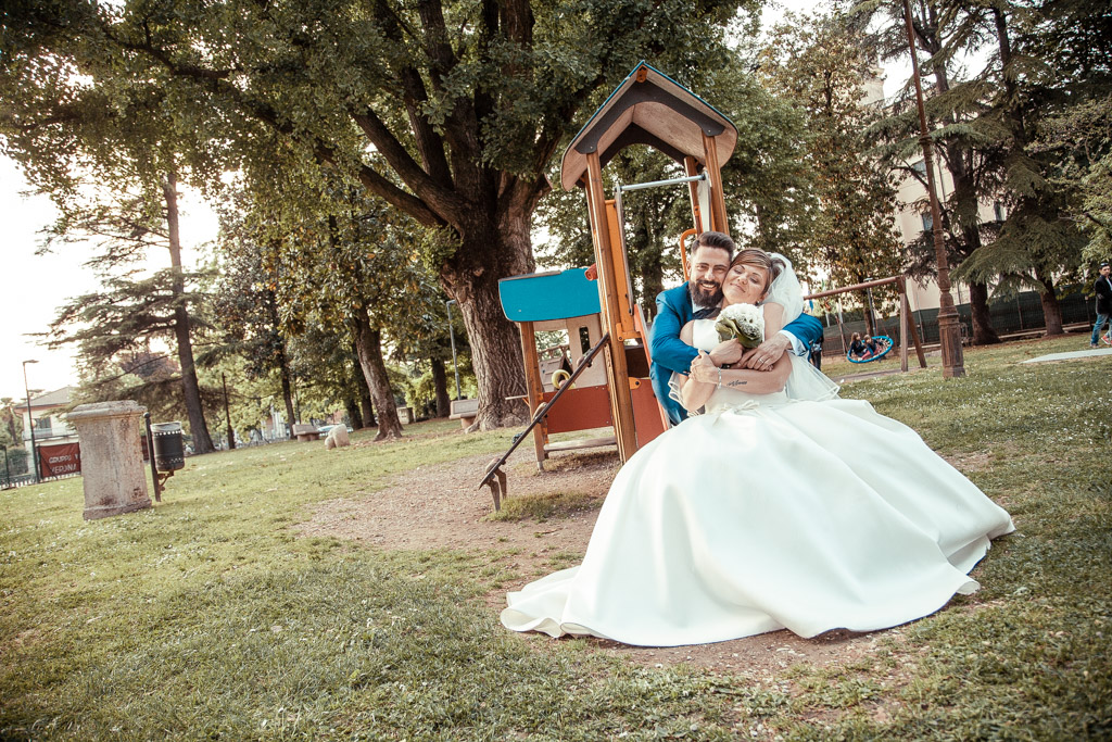 sposi al parco giochi al castello di zevio si abbracciano sullo scivolo