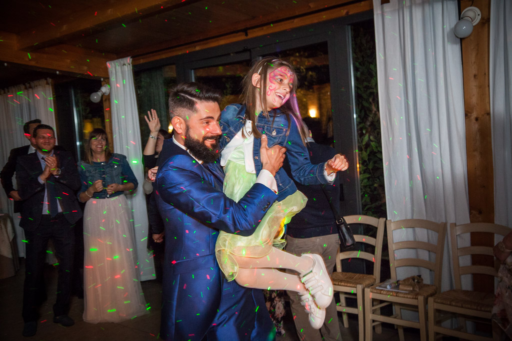 lo sposo prende in braccio una bambina durante la festa